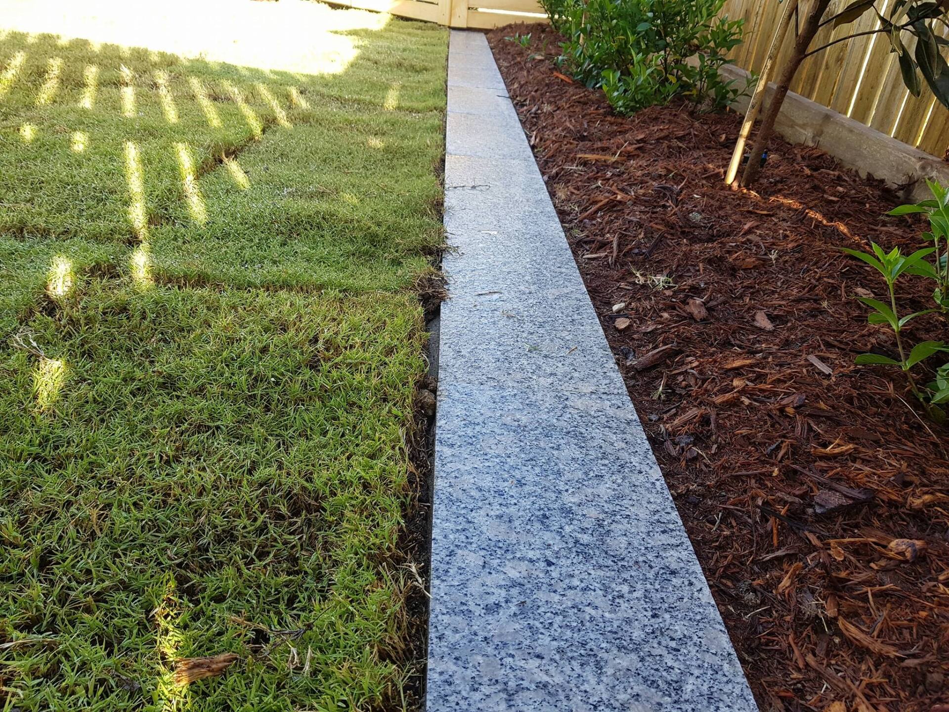 A Walkway Between a Lawn and a Garden With a Fence in the Background — Lynams Landscapes Pty Ltd in Jensen, QLD