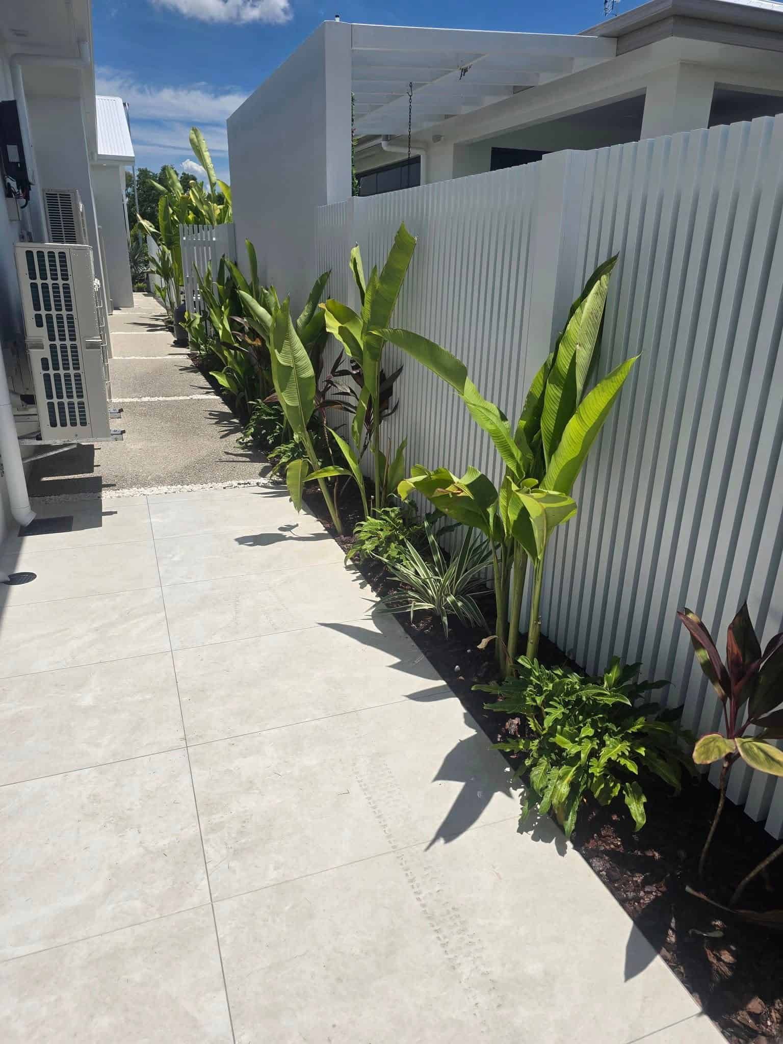 A Walkway Leading to a House With a White Fence and Plants — Lynams Landscapes Pty Ltd in Jensen, QLD
