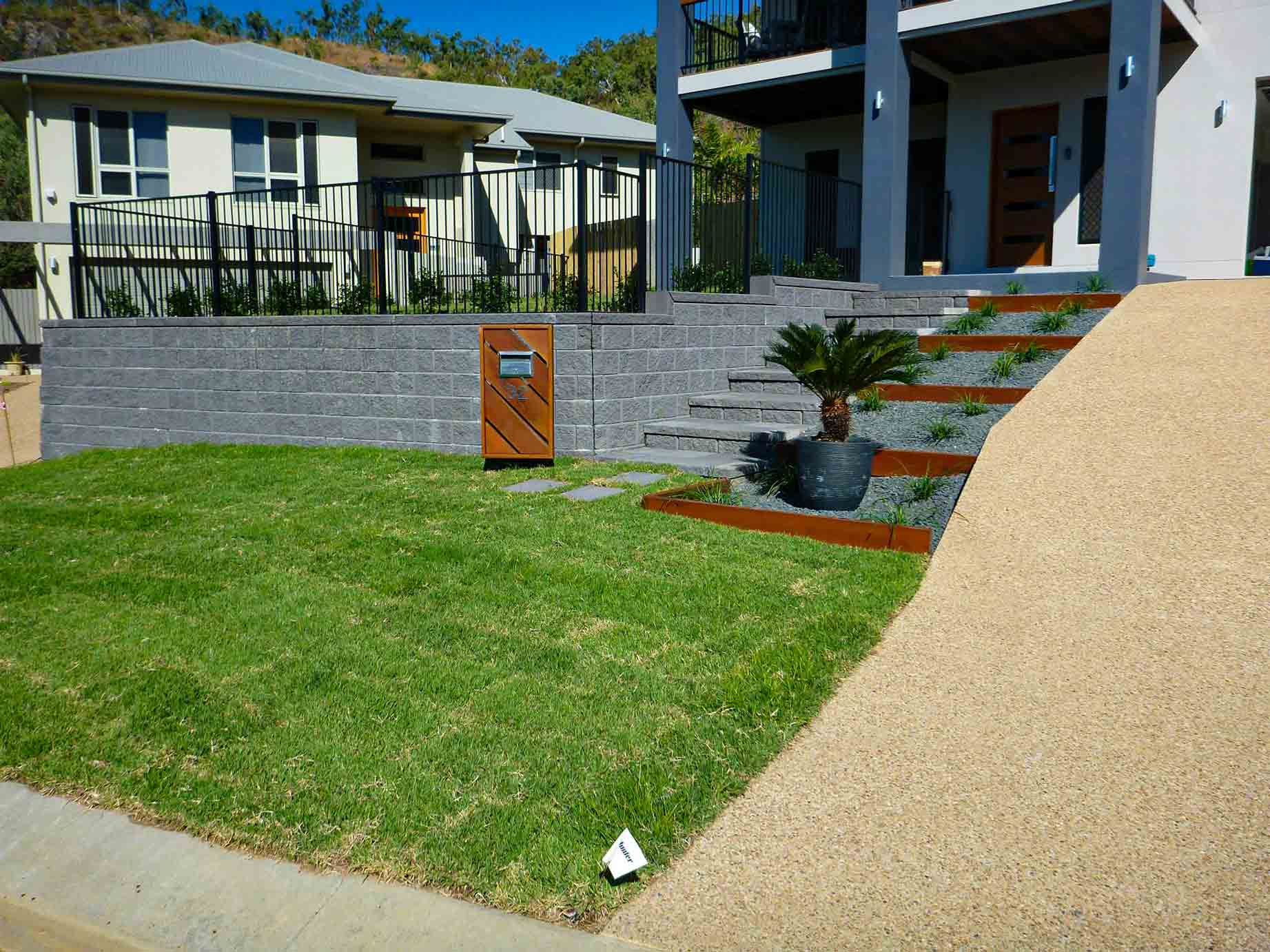 A Brick Wall With Stairs Leading Up to It Next to a House — Lynams Landscapes Pty Ltd in Jensen, QLD