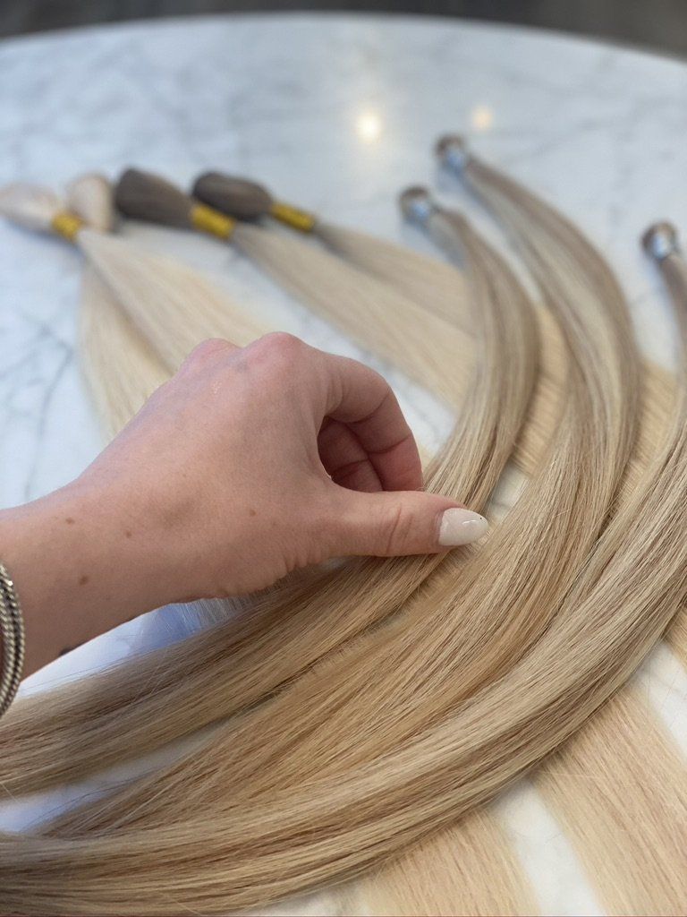 A person is touching a bunch of hair extensions on a table.