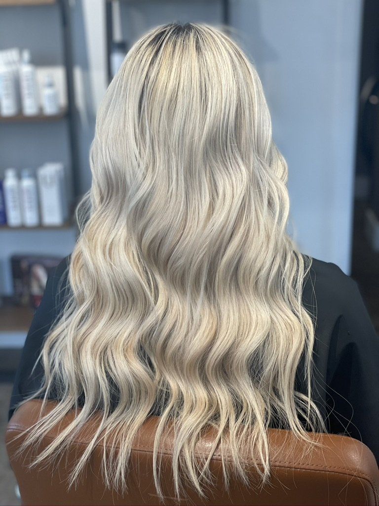 A woman with blonde hair is sitting in a chair in a salon.