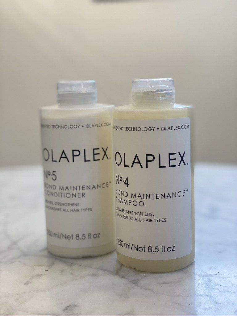 Two bottles of olaplex hair products are sitting on a table.