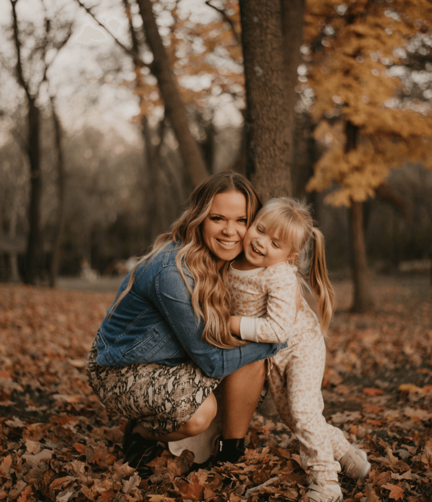 A woman is hugging a little girl in a park.