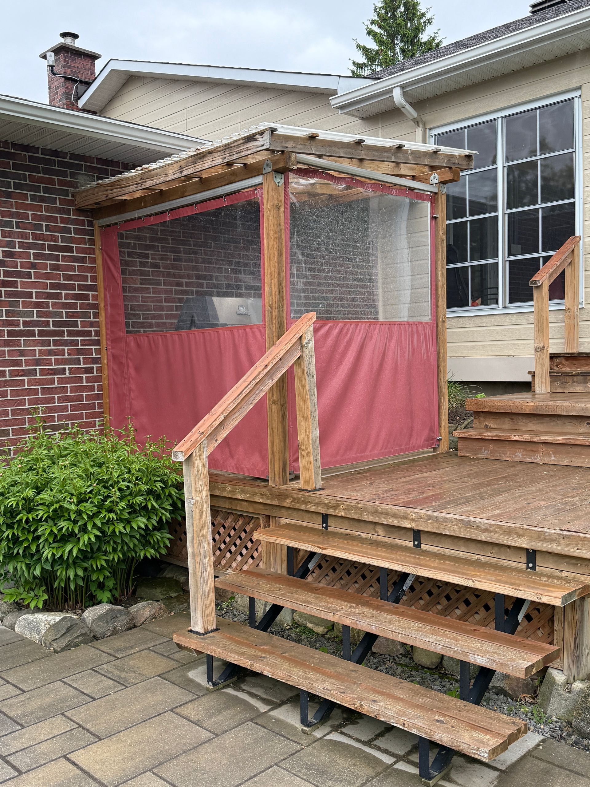 Une terrasse en bois avec des escaliers et un rideau rouge dessus.