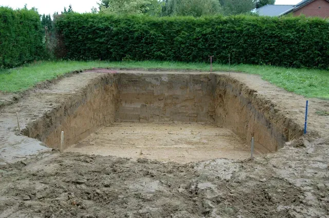 Un grand trou dans le sol est en train d'être rempli de terre