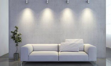 Minimalist living room with a white sofa, potted plant, and wall spotlights on a gray wall. Minimalist living room with a white sofa, potted plant, and wall spotlights on a gray wall.