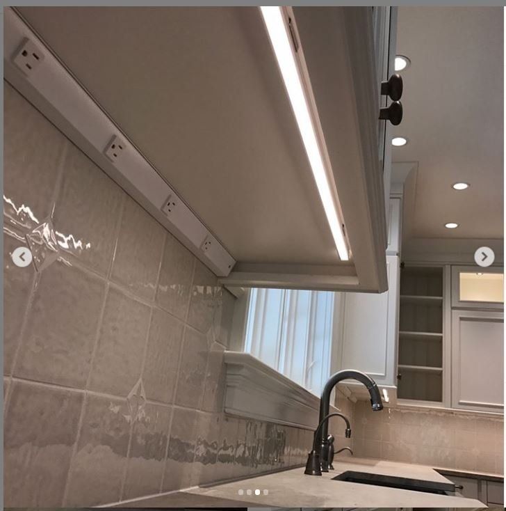 Modern kitchen with beige tile backsplash, black faucet, sink, and under-cabinet lighting