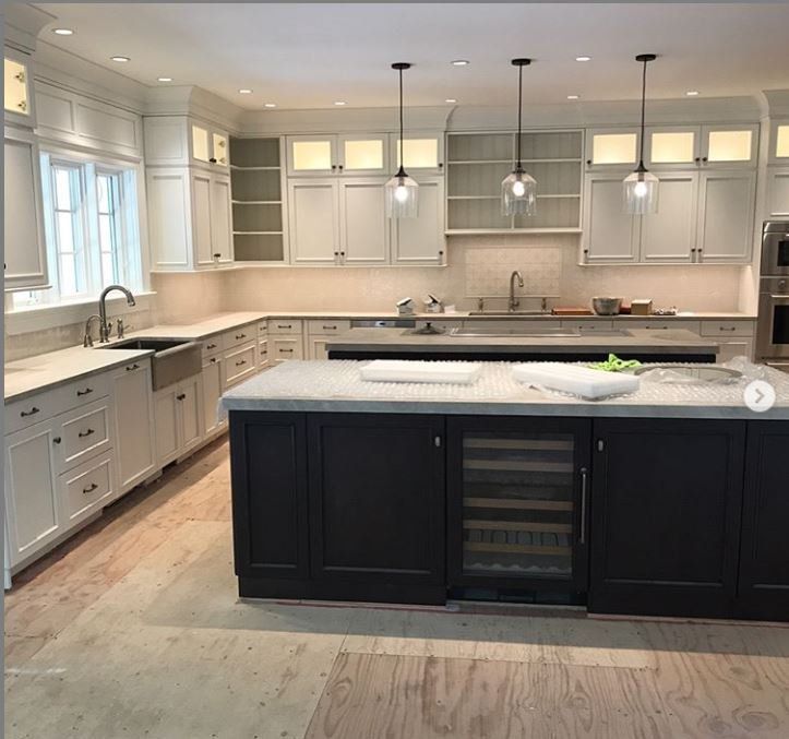 Modern white kitchen with a dark island, stainless fixtures, and pendant lights
