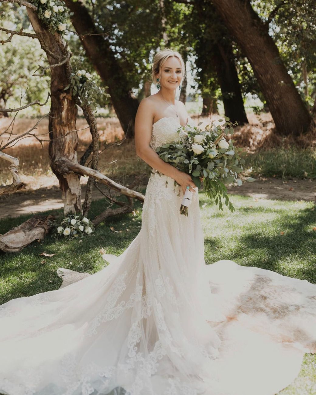 A bride in a wedding dress is holding a bouquet of flowers.
