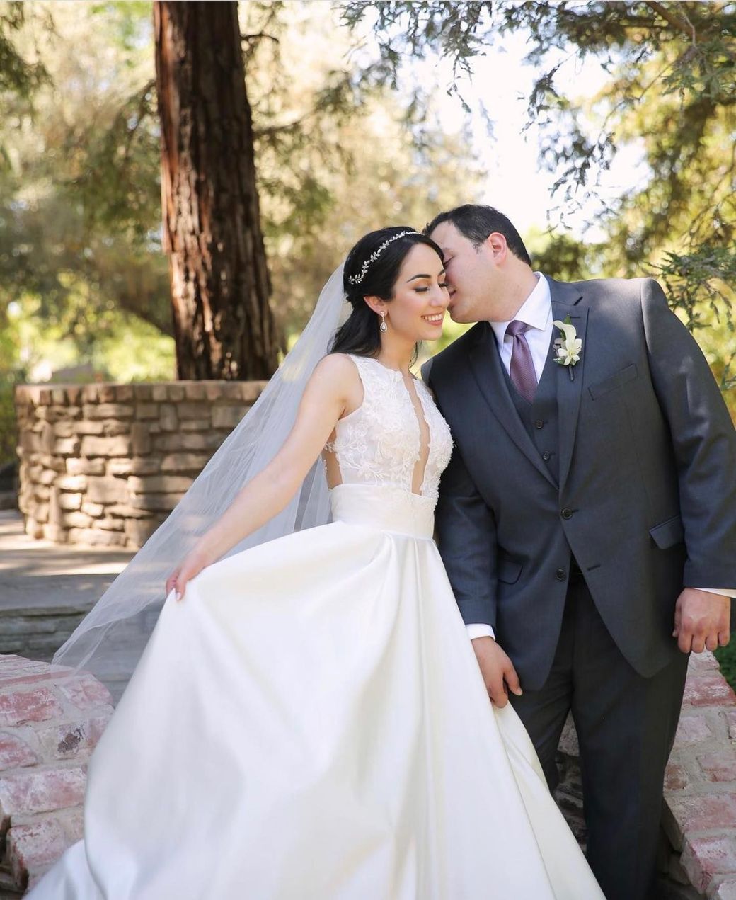 A bride and groom kissing in front of a tree