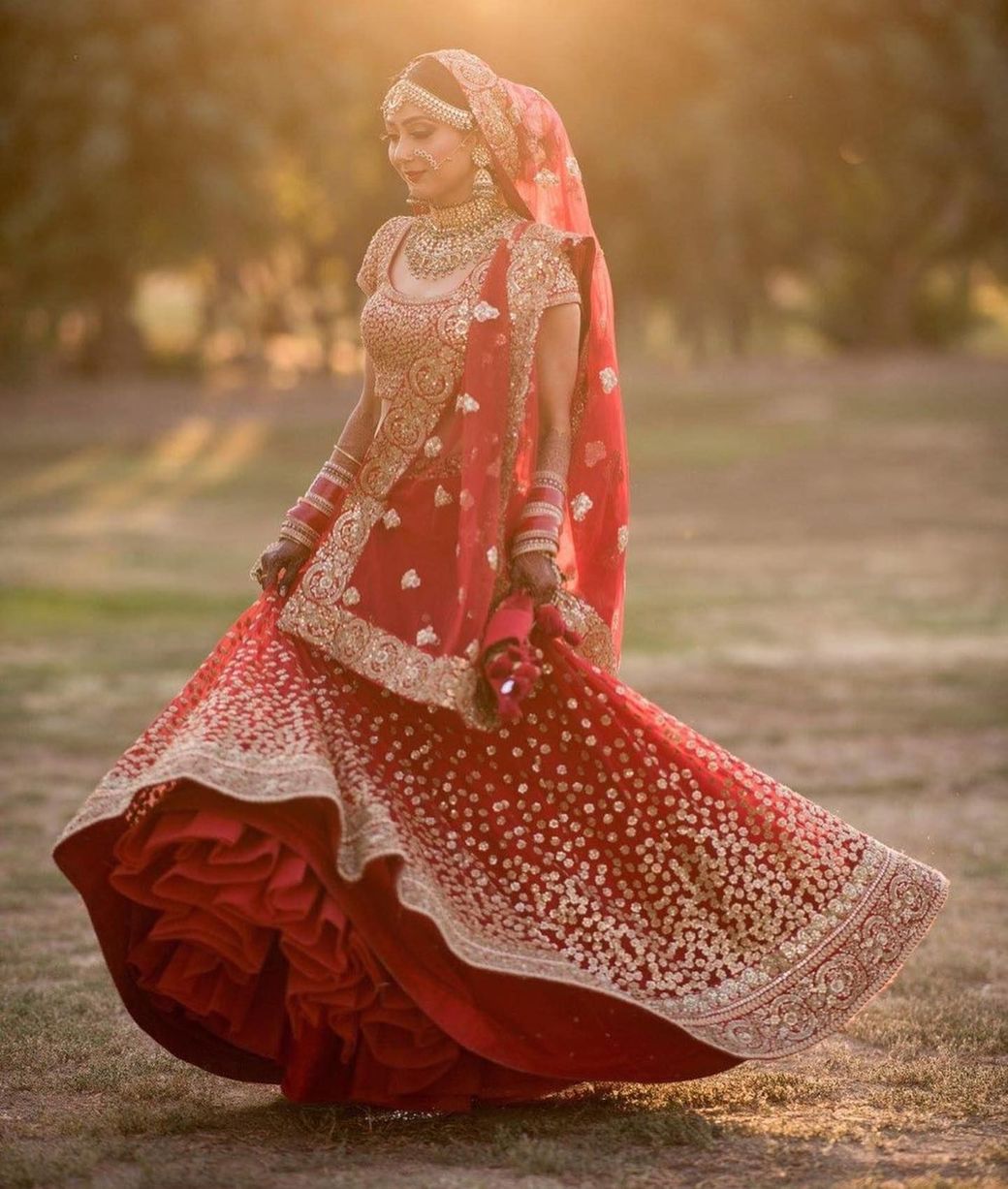 The bride is wearing a red and gold dress and holding a bouquet of flowers.