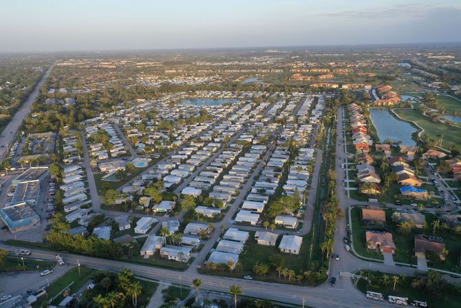 Aerial view of a suburban neighborhood with rows of houses, roads, and a canal at sunset.