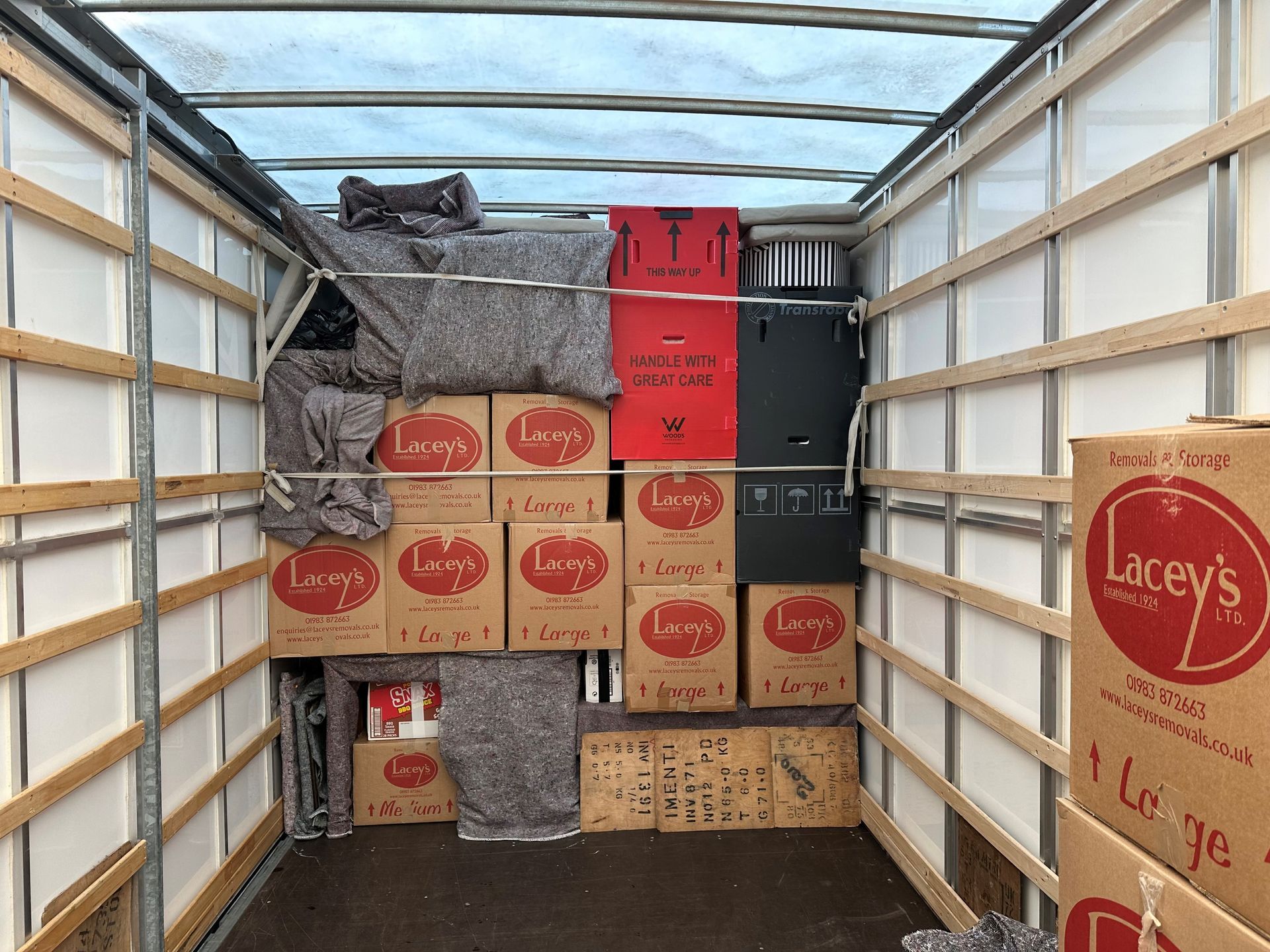 Interior of a truck filled with moving boxes and blankets; boxes are labeled 