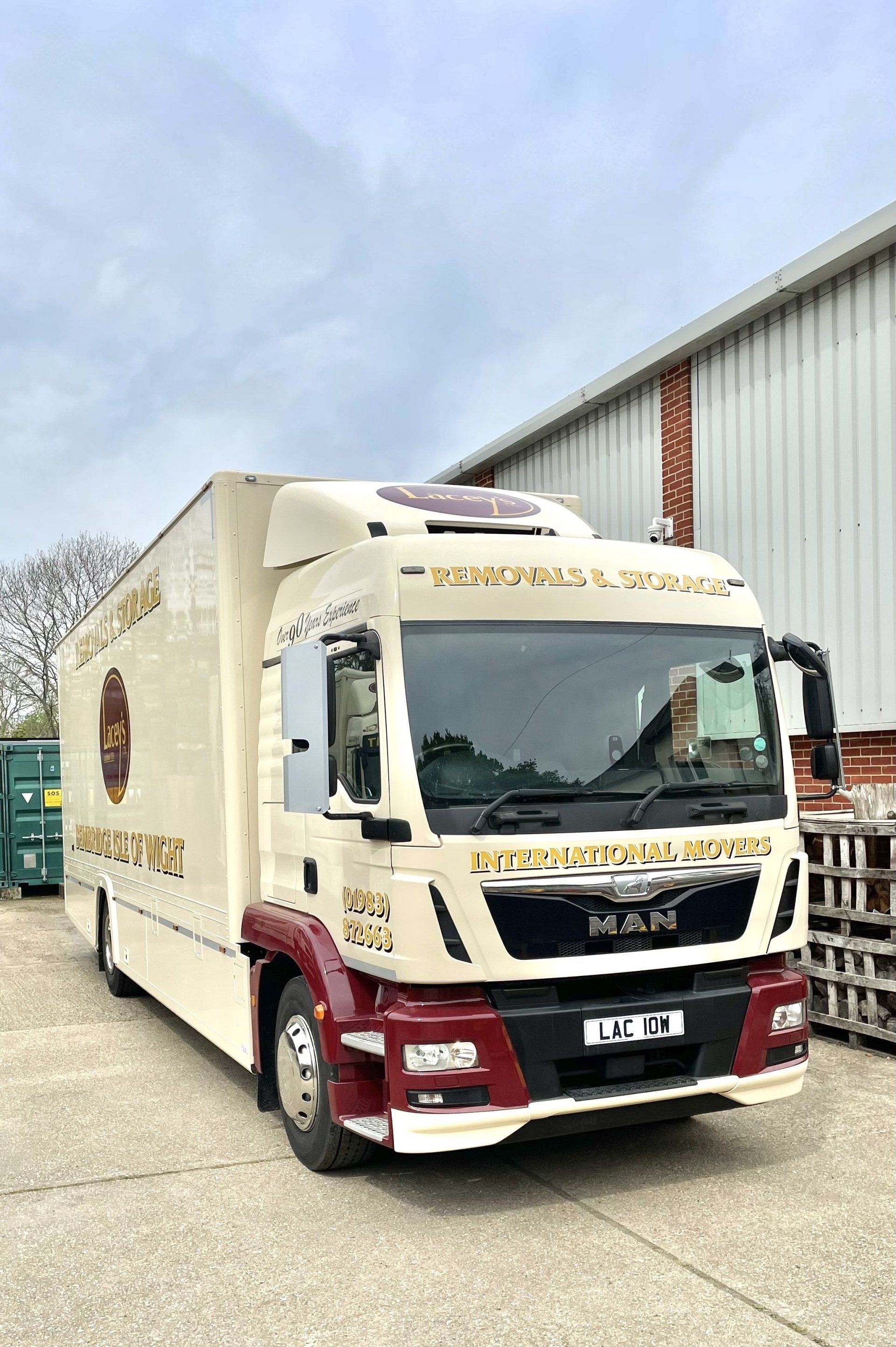 Cream and maroon MAN truck with company branding parked outside a building.