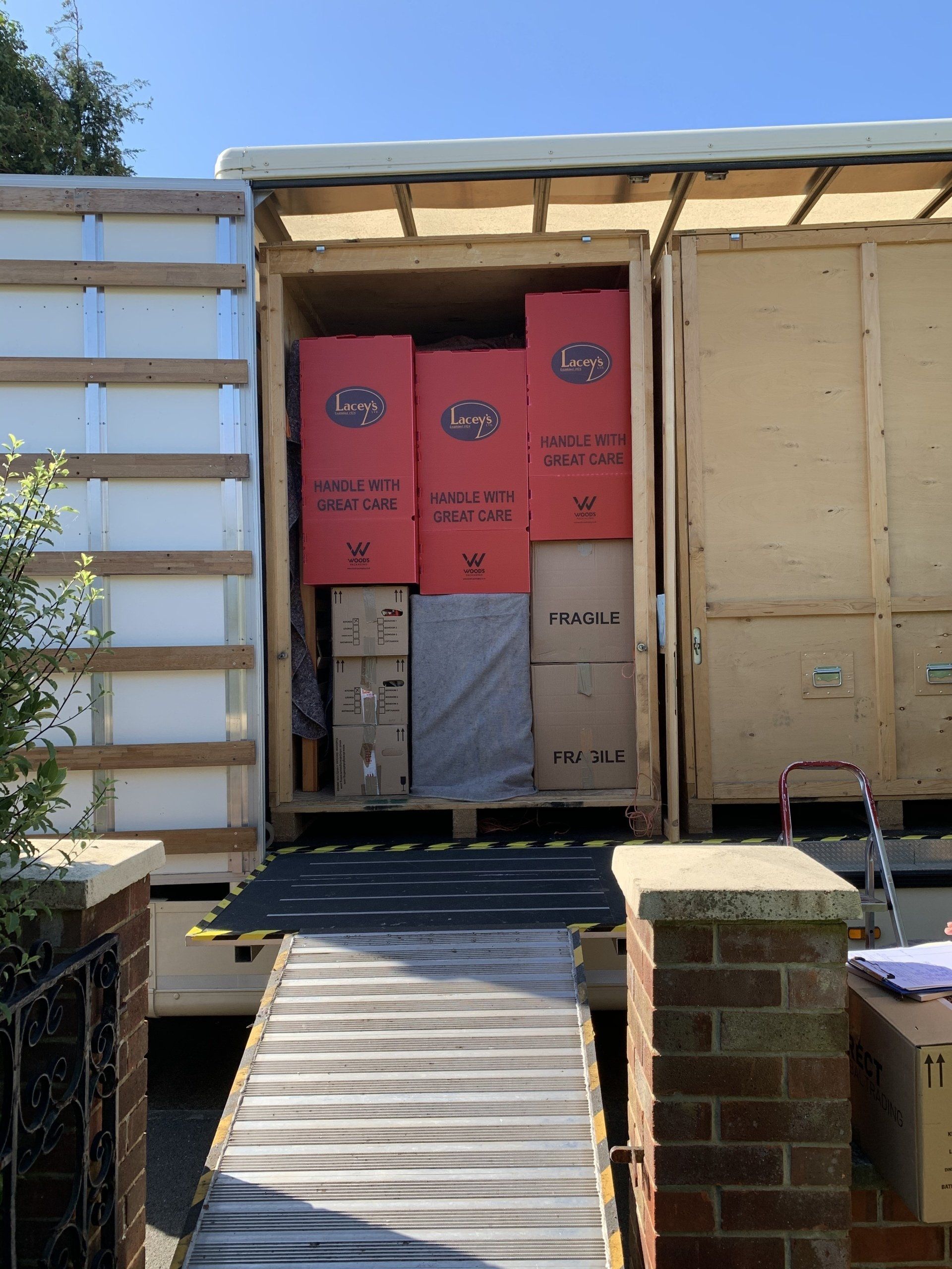 Boxes being loaded into a moving truck with a ramp, bright sunlight.