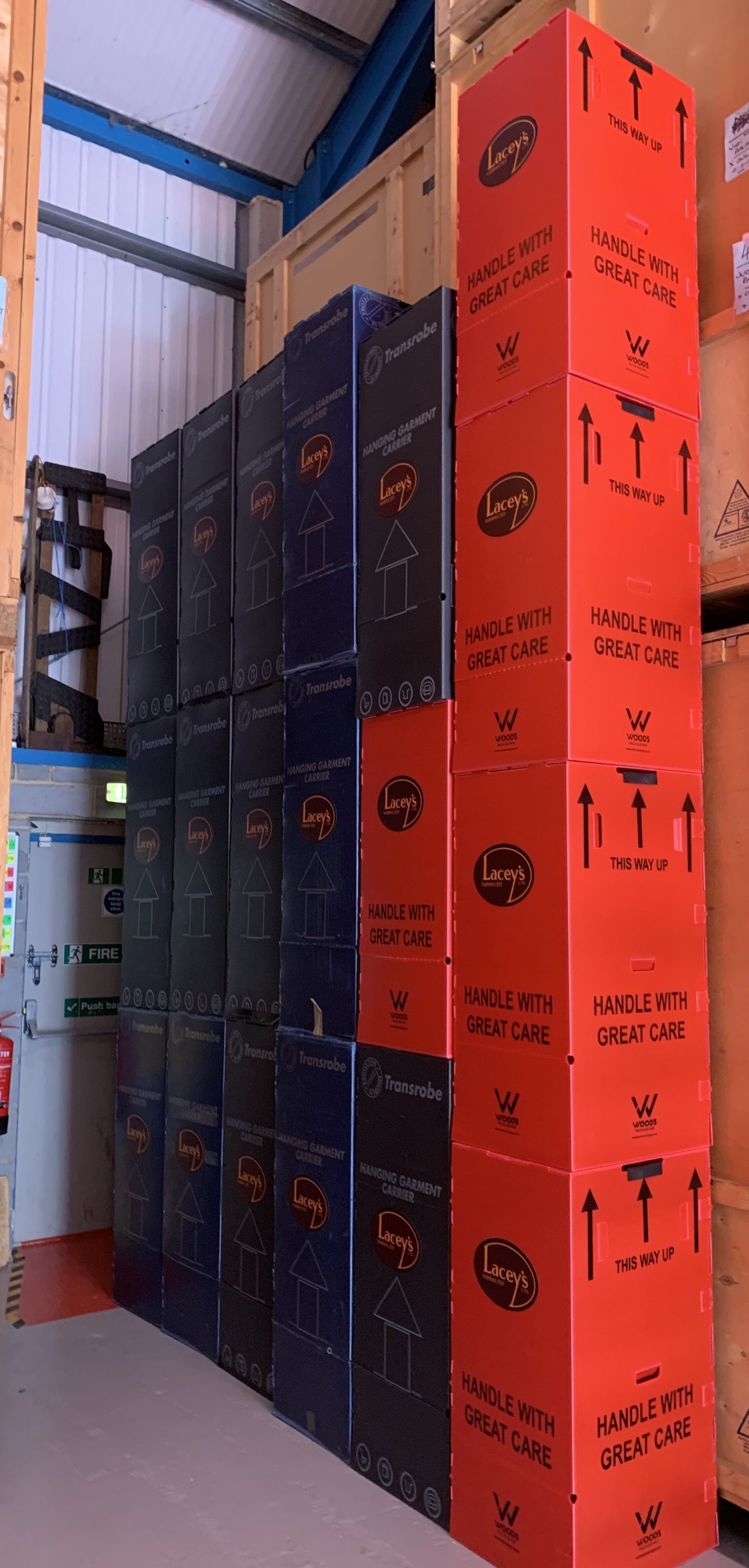 Rows of stacked boxes, mostly blue and red, in a warehouse setting.