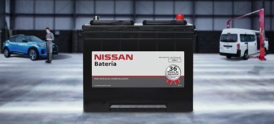 Batería de coche Nissan centrada en un terreno nevado, con un coche azul y una furgoneta blanca al fondo.