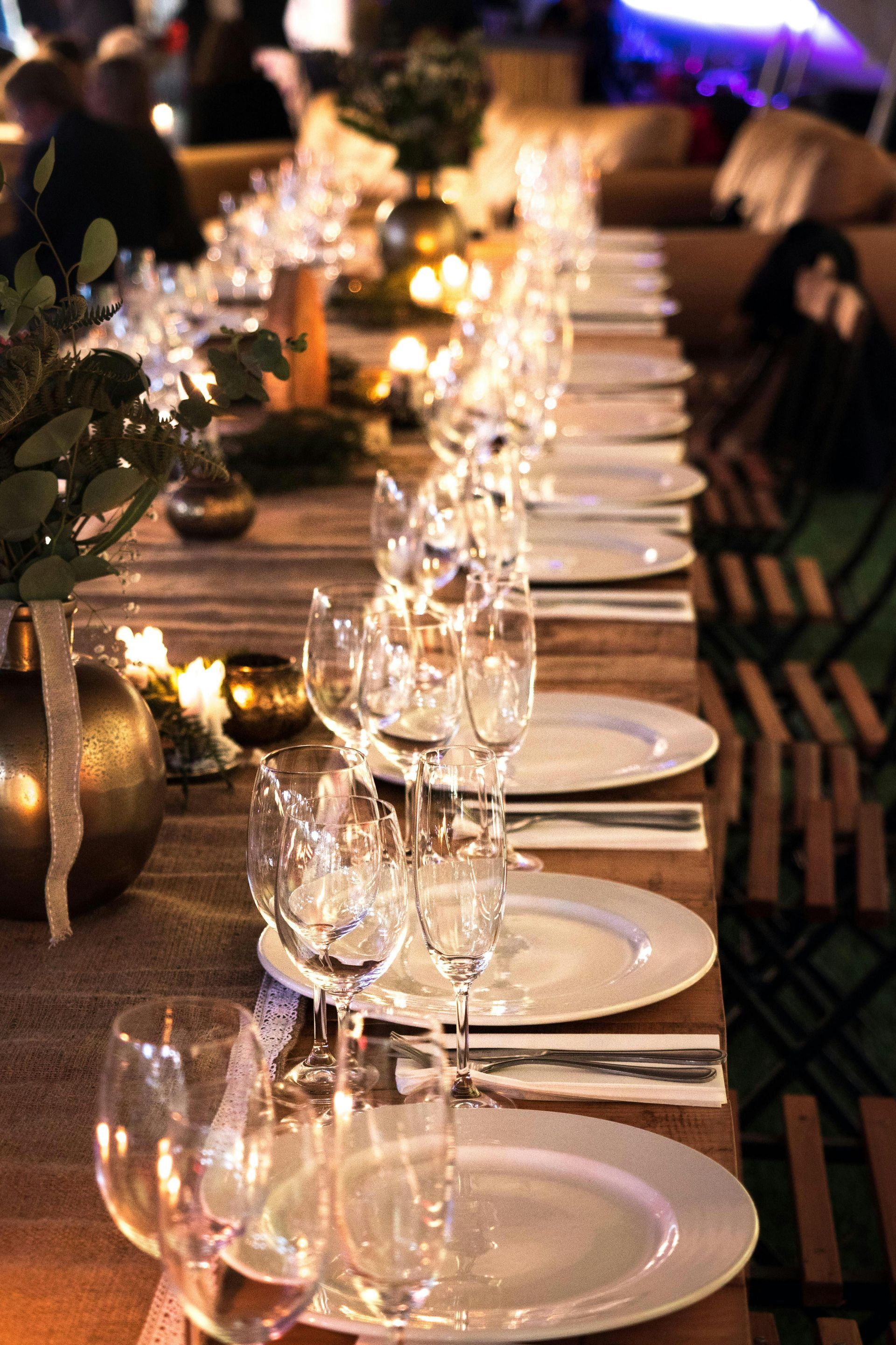 A long table set for a dinner party with plates , glasses , and silverware.