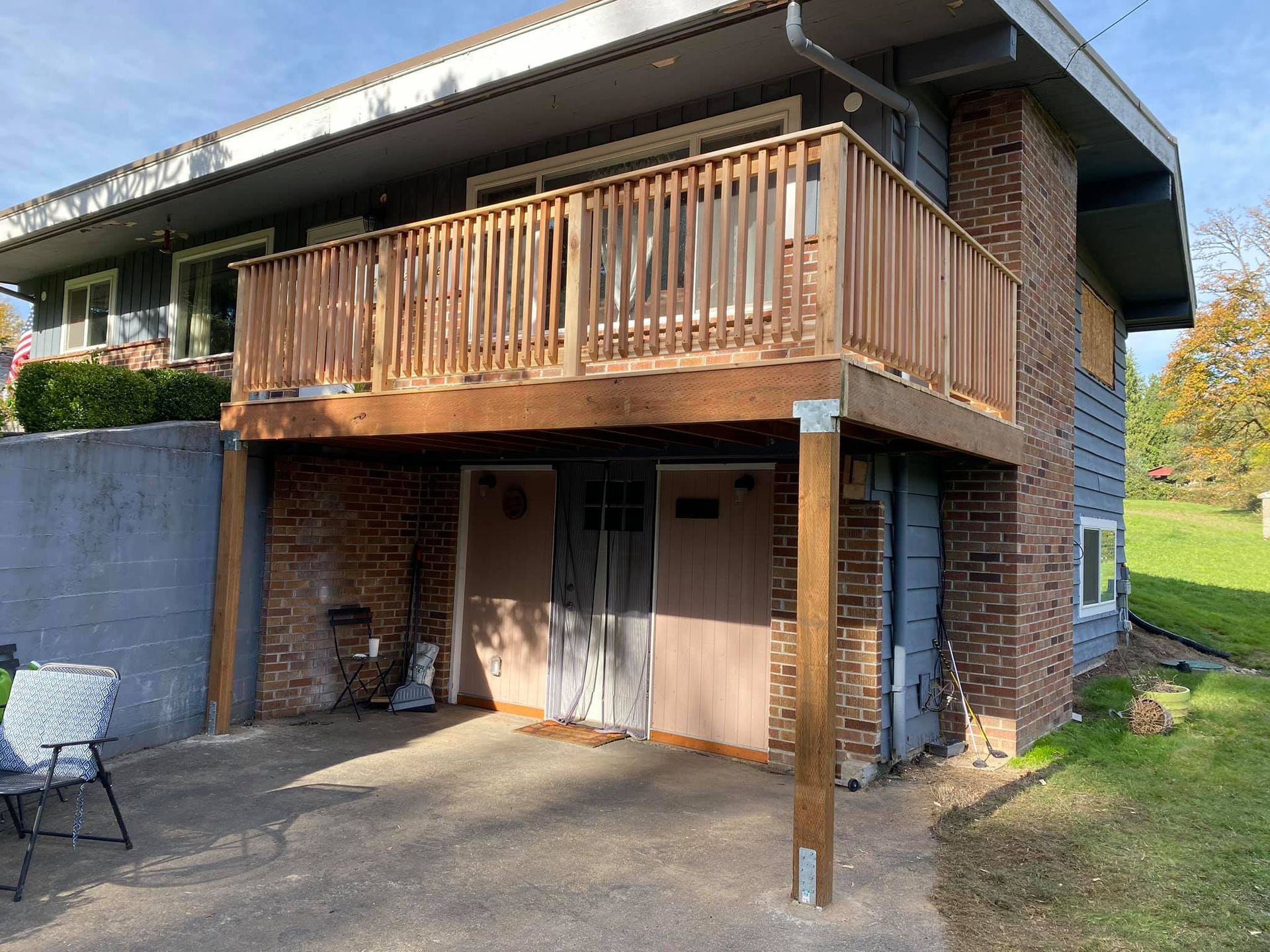 A house with a wooden deck and a garage underneath it.