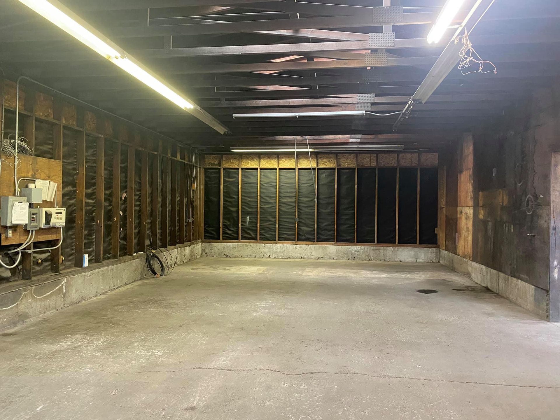 An empty garage with wooden walls and a concrete floor.