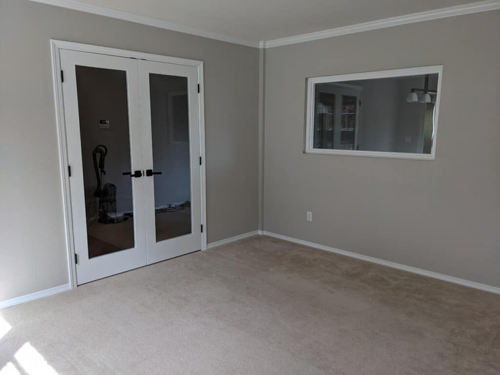 A living room with a vacuum cleaner in it and a large mirror on the wall.