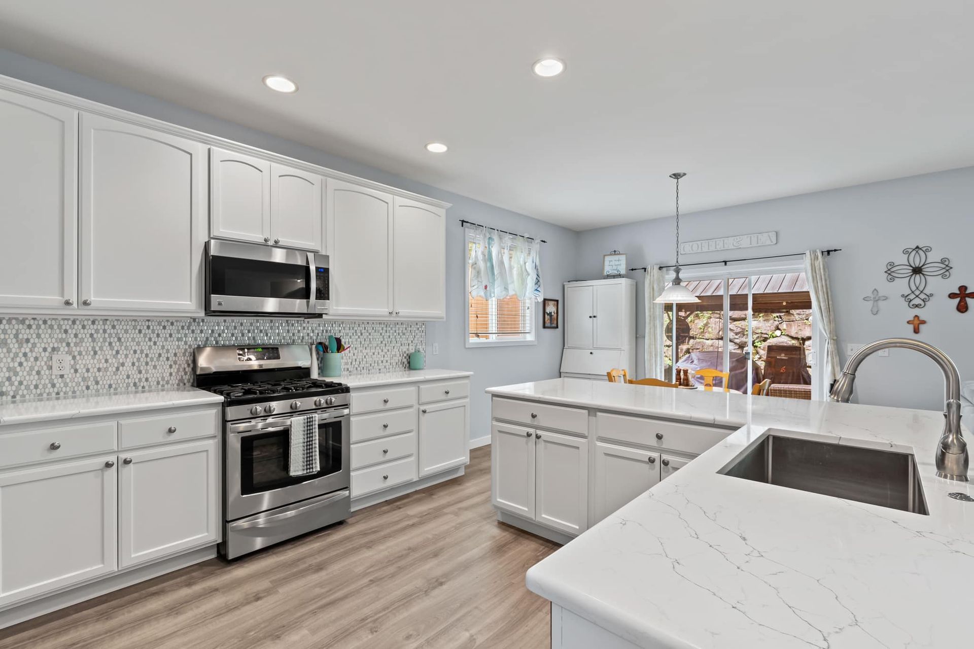 A kitchen with white cabinets , stainless steel appliances , a sink , and a stove.