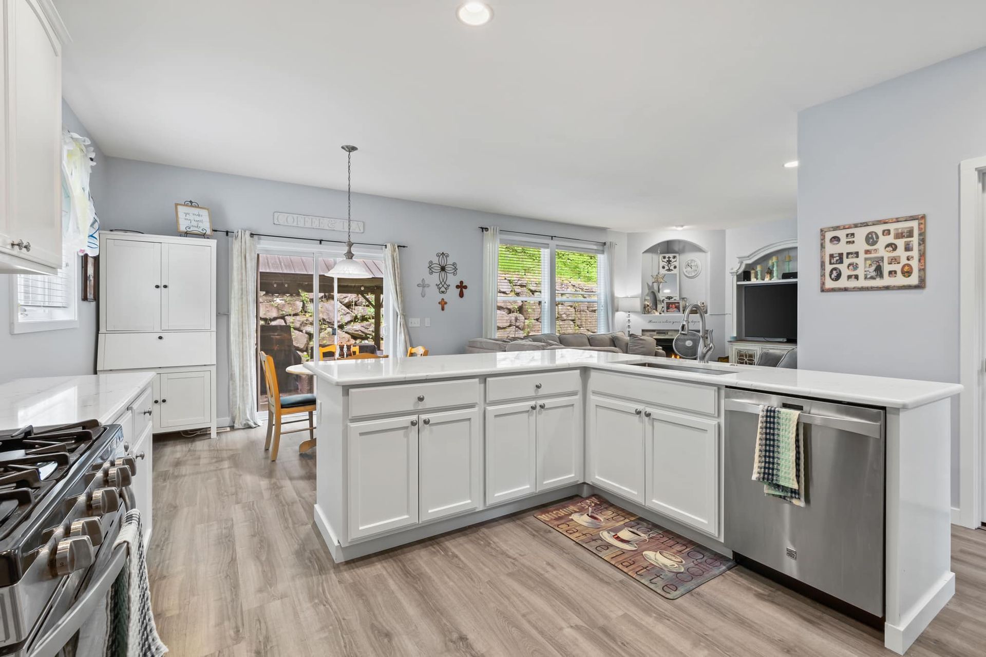 A kitchen with white cabinets , stainless steel appliances , and a large island.
