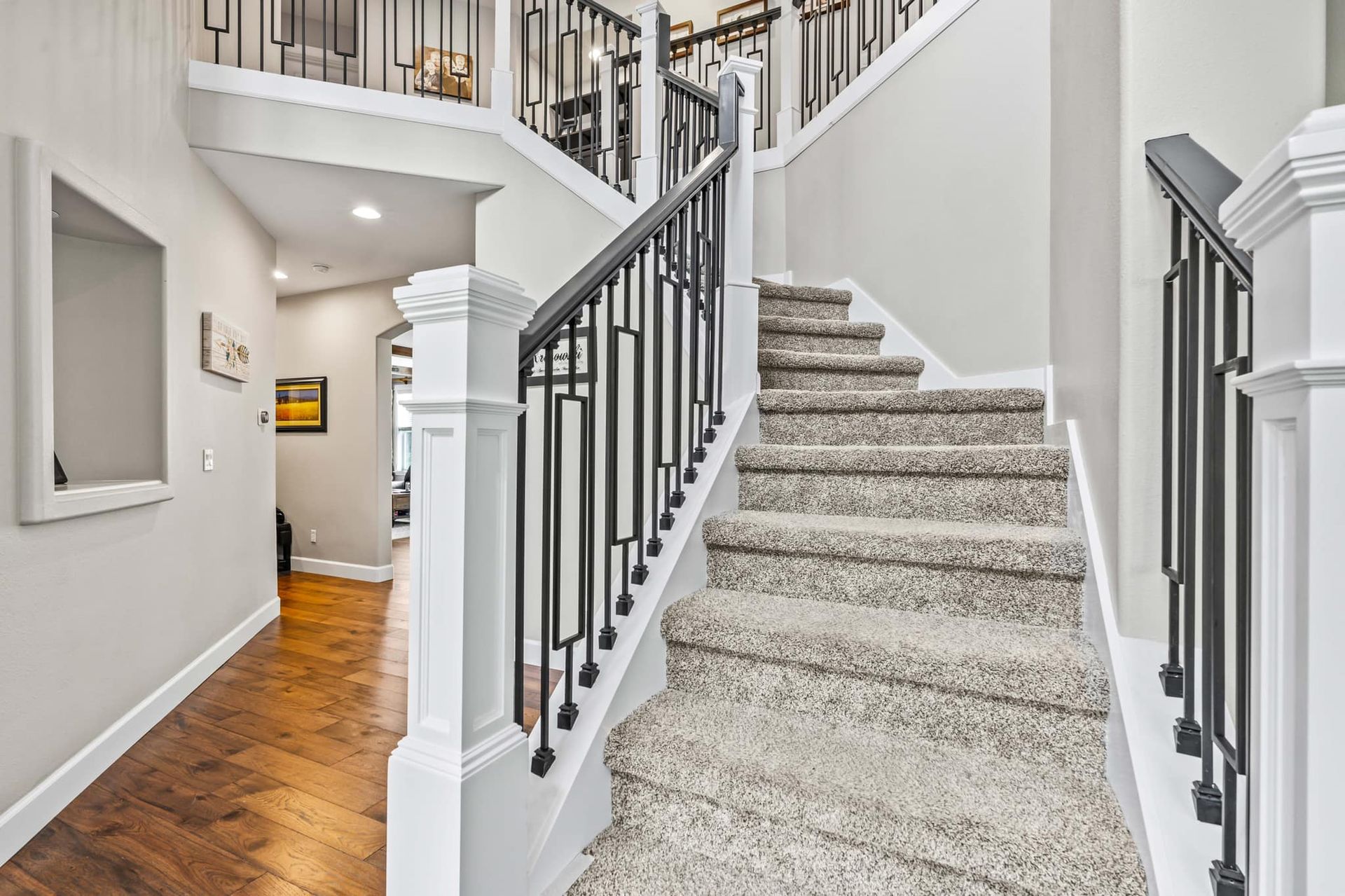 A staircase in a house with a black railing and carpeted steps.