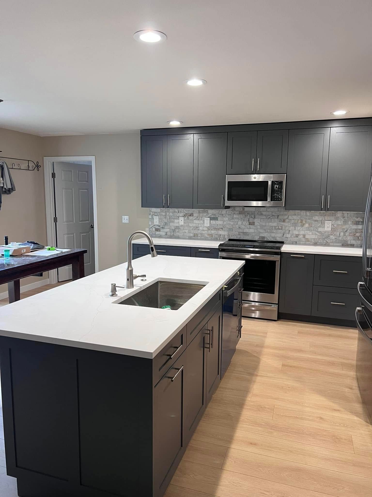 A kitchen with a large island , sink , stove and microwave.