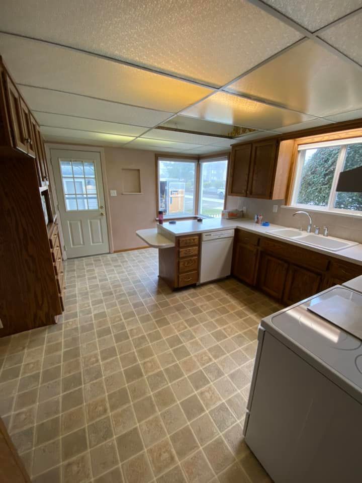 A kitchen with wooden cabinets , a stove , a dishwasher , and a window.