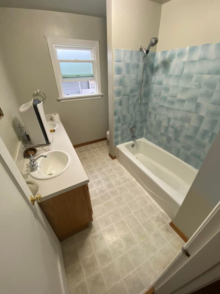 A bathroom with a sink , tub , shower and window.