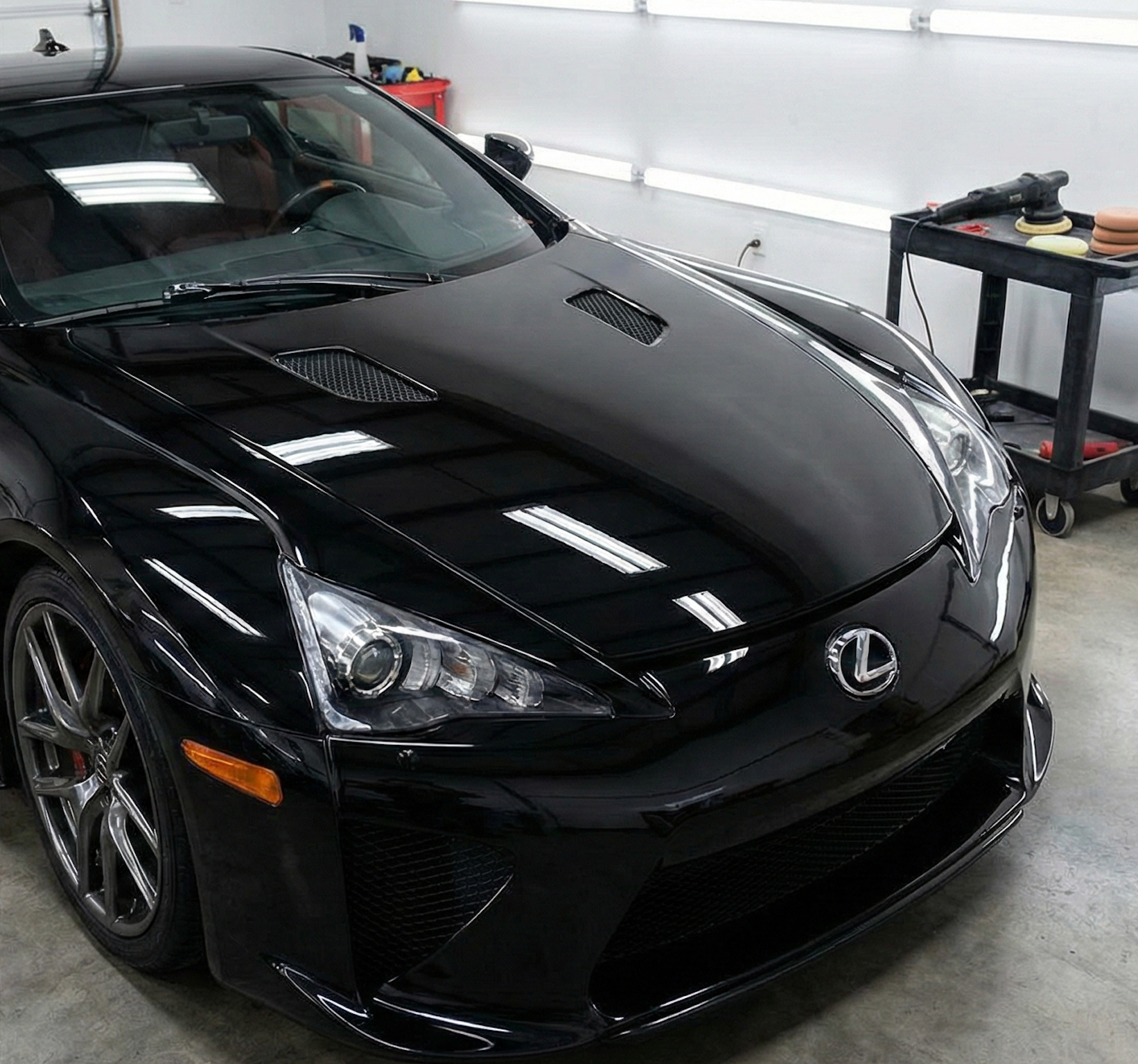 Black Lexus sports car in a garage, front view with glossy hood and headlights on display