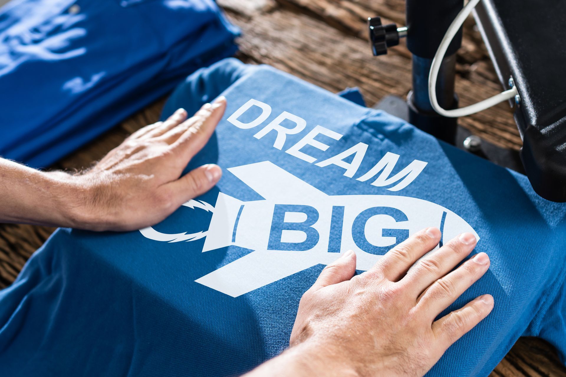 Person pressing a heat press on a blue t-shirt printed with