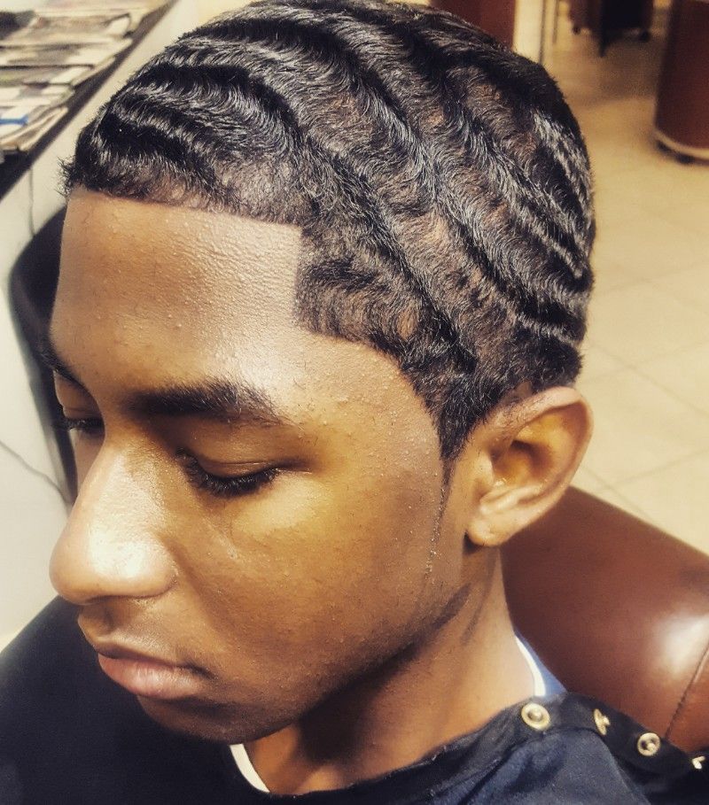 A young man with waves in his hair is sitting in a chair