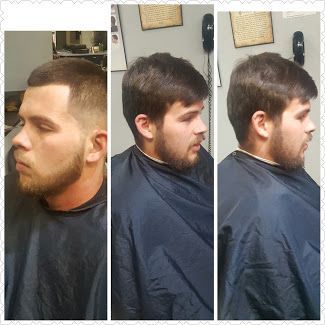 A man with a beard is getting his hair cut at a barber shop.
