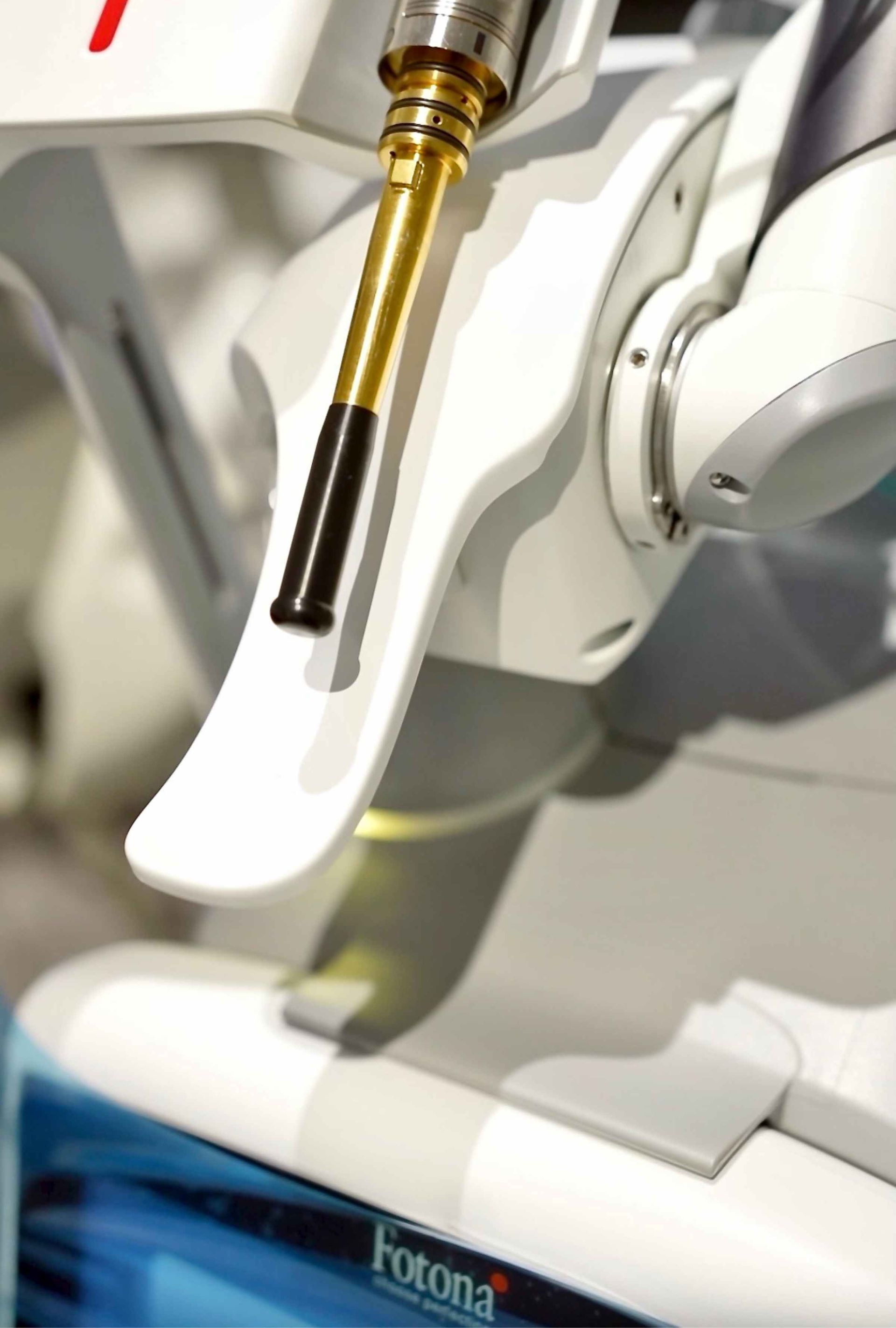 Close-up of a white medical device with a gold and black instrument arm, likely a laser, bearing the Fotona logo.