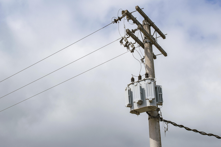 Utility pole with transformers and power lines against a cloudy sky