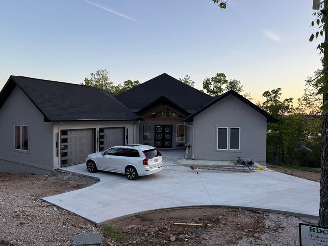 New gray house with a white SUV parked in the driveway at dusk