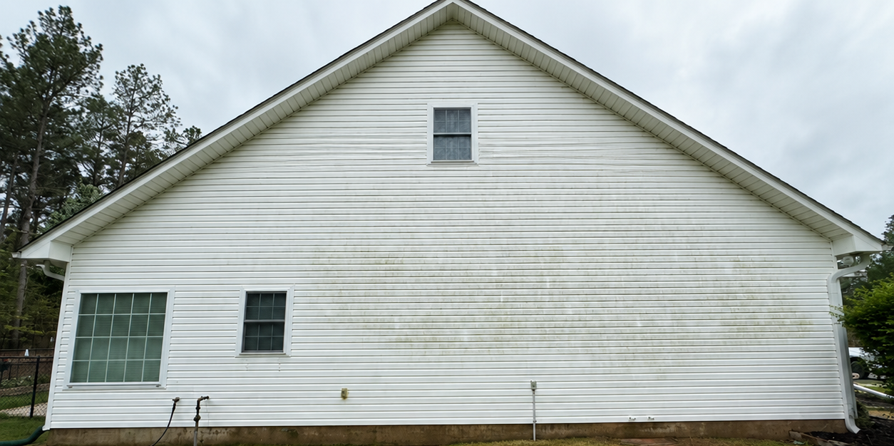 White house side view with horizontal siding, small windows, and a gabled roof.