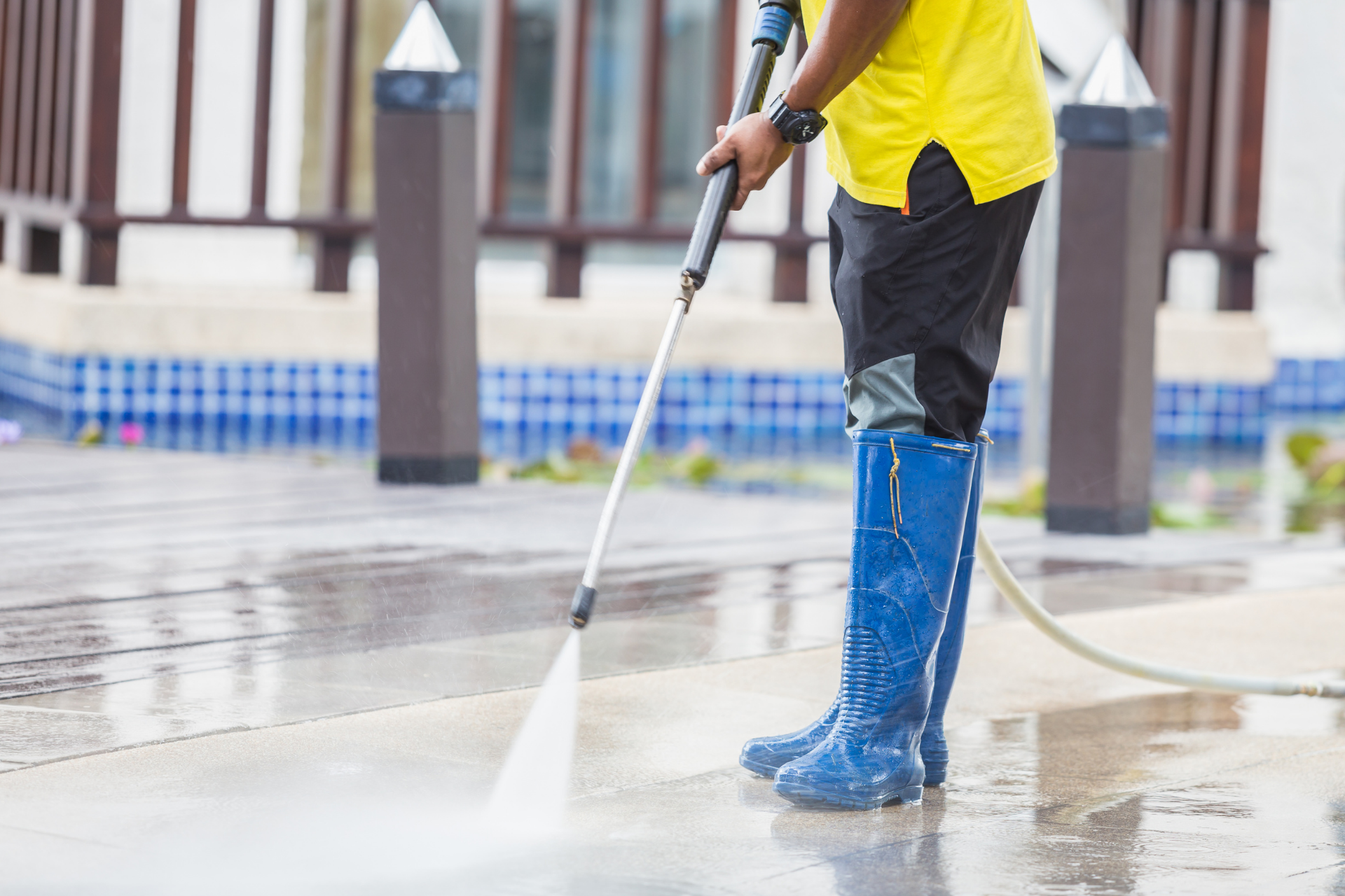 Worker using a floor grinder on concrete, with a blue hose in an outdoor work area