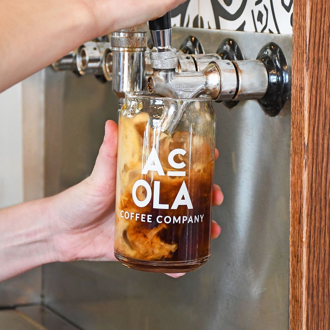 Hand holding Acola Coffee iced drink under espresso tap at Acola Coffee Company Columbia MO