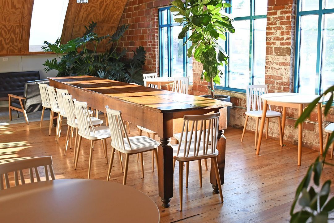 Interior dining area with wooden tables plants and exposed brick at Acola Coffee Company Columbia MO