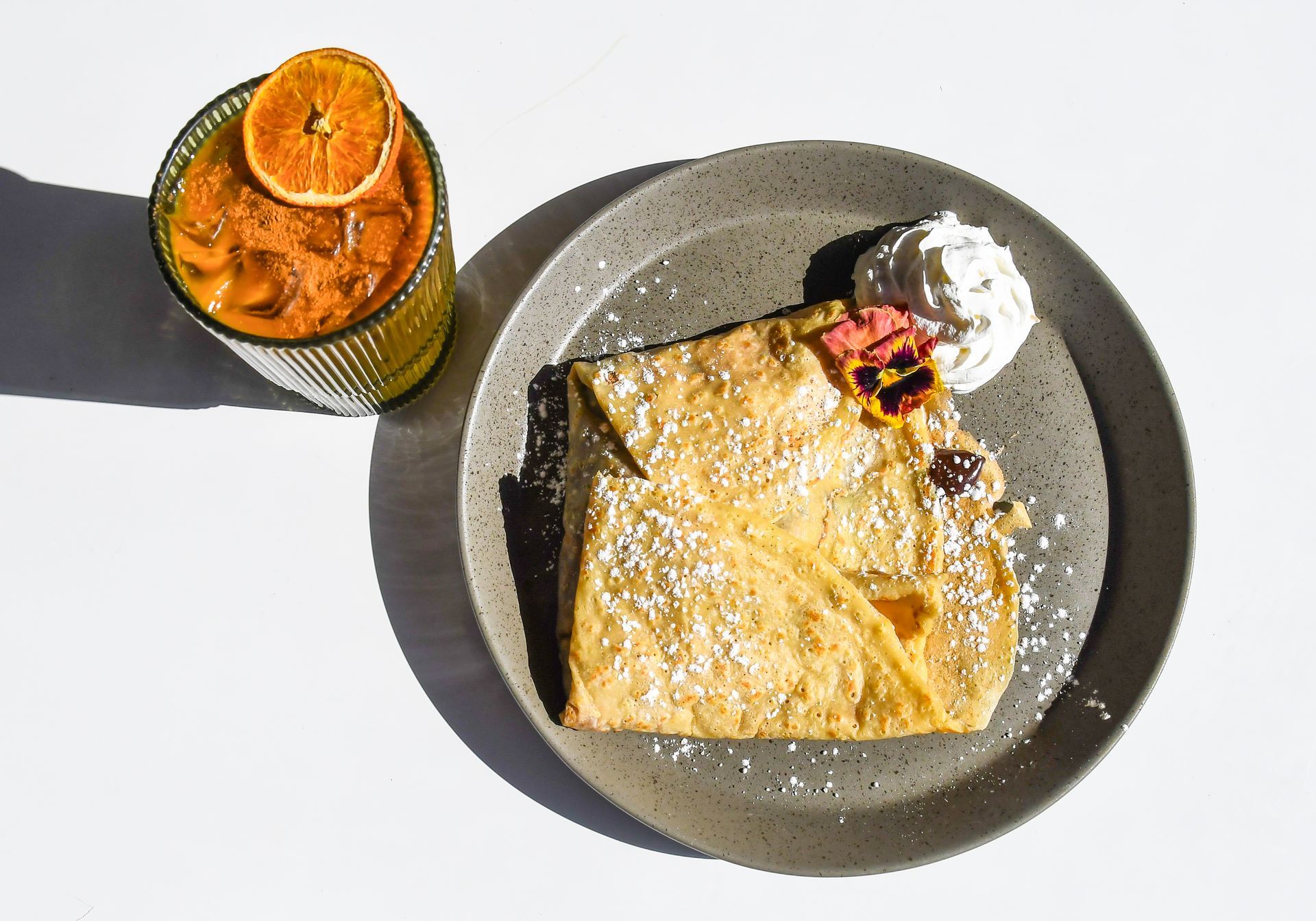 Sweet crepe with berries powdered sugar and whipped cream served on a plate at Acola Coffee Company Columbia MO