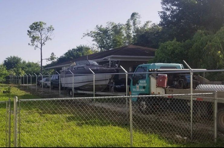 A boat is on a trailer behind a chain link fence