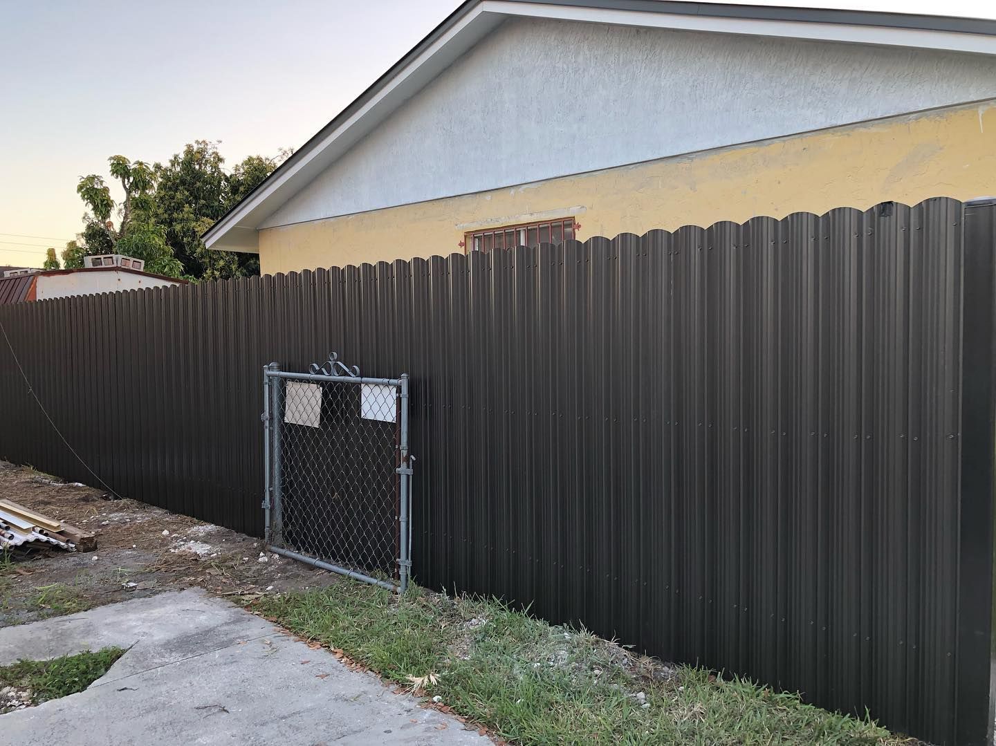 A brown fence is surrounding a house with a chain link fence.
