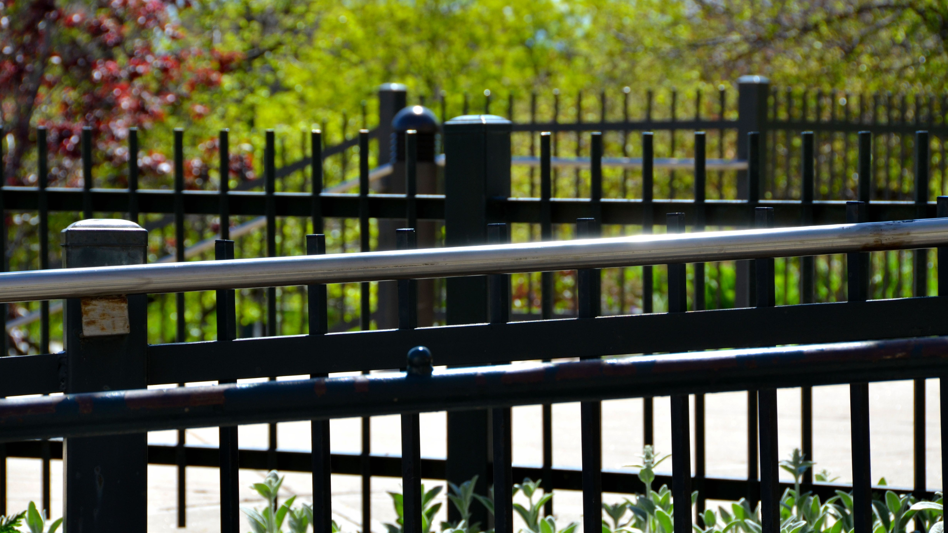 A close up of a black fence with trees in the background