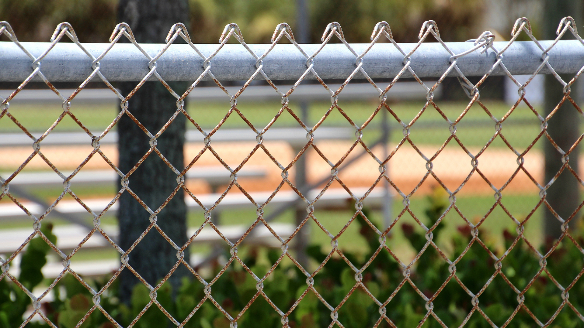 A chain link fence with a baseball field in the background