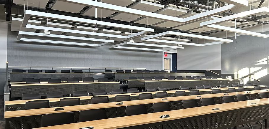 A large lecture hall with rows of tables and chairs.