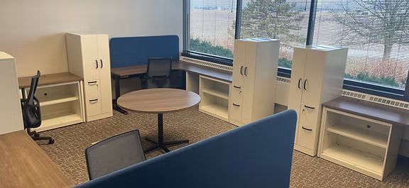 A room with a table , chairs , cabinets and a window.