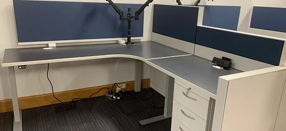 A cubicle with a desk and drawers in an office.